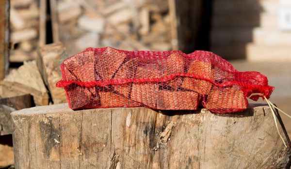 Firewood stacked in red net sack and placed on the stump.